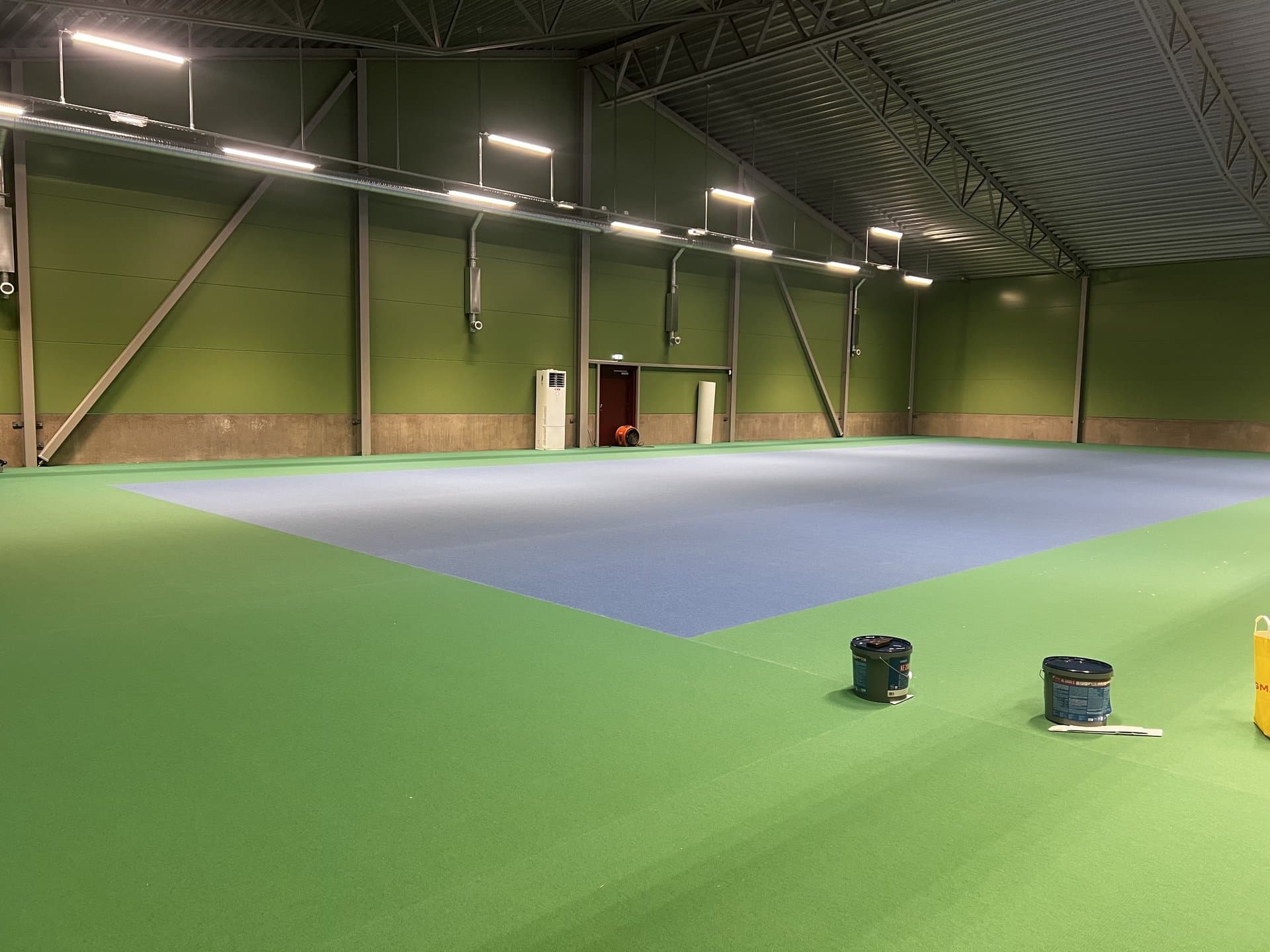 Färdig sportgolv-installation — idrottshall med ljusblå spelplan på grön bakgrund